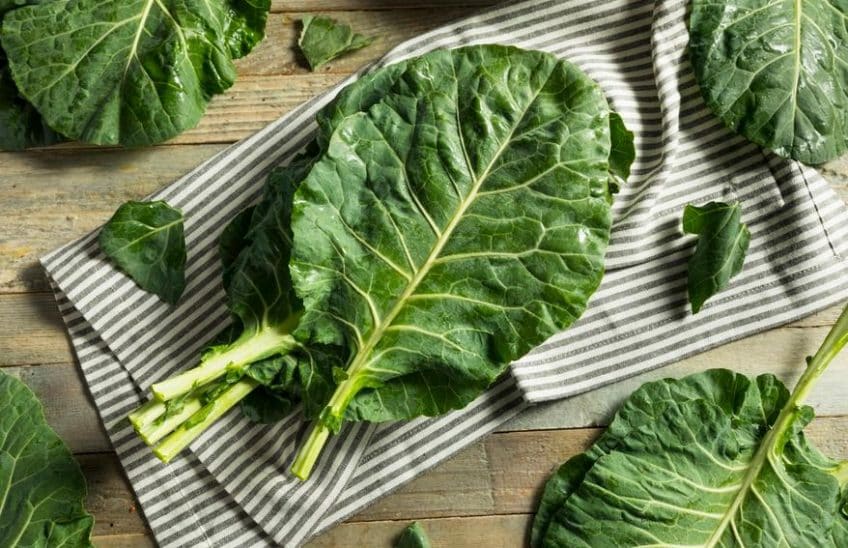 Fresh collard greens lying on a striped dish towel.