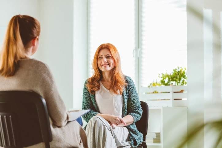 Two women seated facing one another and talking.