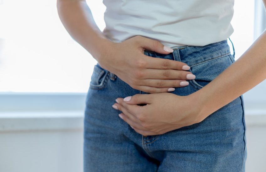 A woman holding her hands to her stomach in pain.