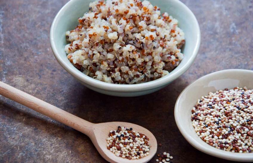Two bowls of cooked and uncooked quinoa on a countertop