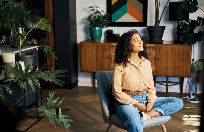 A seated woman practicing mindfulness meditation in her living room