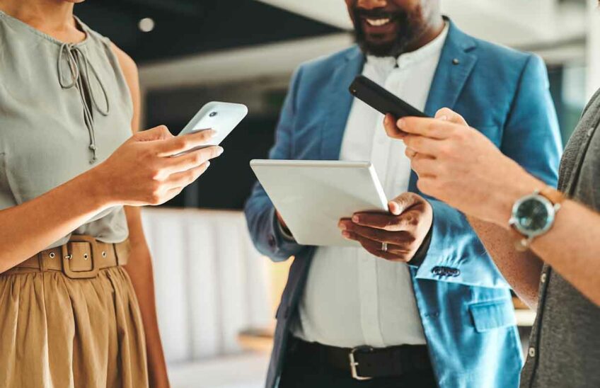 Three people talking to each other while using mobile devices