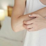 A person scratching a dry, itchy elbow