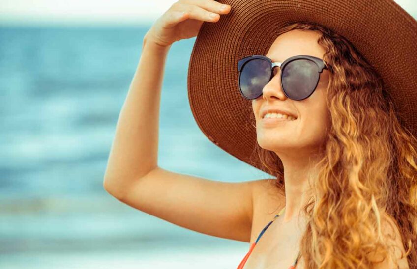 Woman at the beach wearing sunglasses and a straw hat