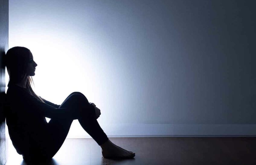 Teenager with depression sitting alone in dark room